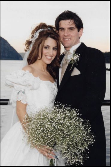 A happy bride and groom posing outdoors on their wedding day.