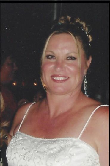 Smiling woman in white dress with elegant earrings at an event.