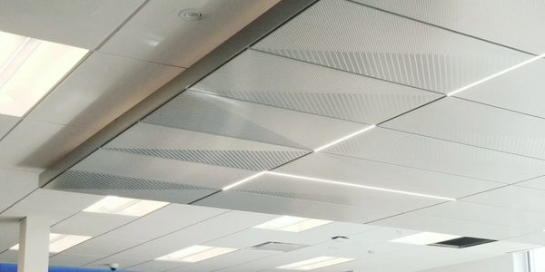 Modern office ceiling with recessed lighting and blue glass wall.