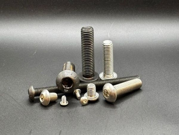 Various metal screws and bolts on a gray surface.