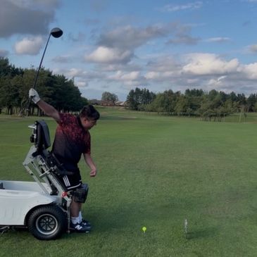 A person in a specialized wheelchair playing golf on a sunny day.