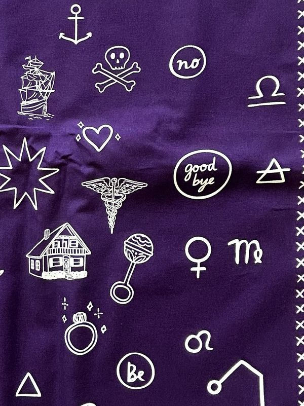 Purple fabric with various white symbols and words.