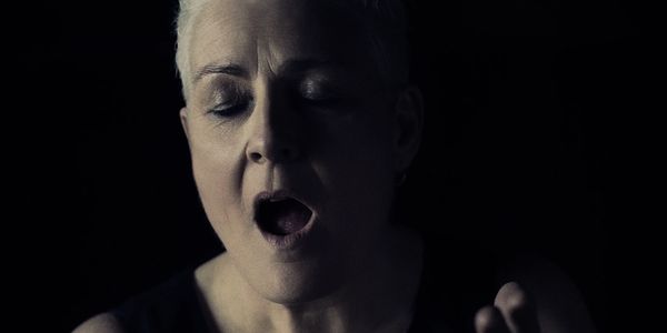 A person singing or expressing emotion with eyes closed.