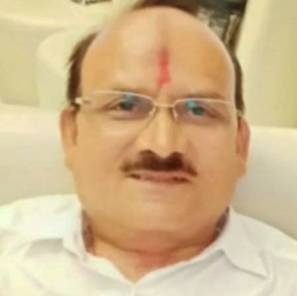 Middle-aged man with glasses and a red tilak on forehead.