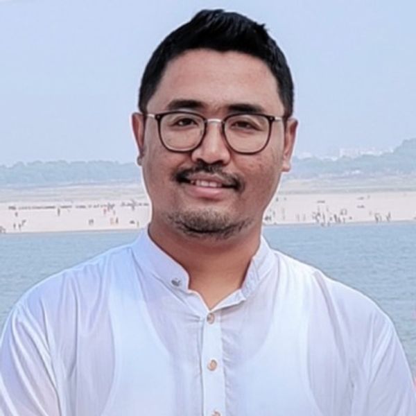 Man wearing glasses and white shirt by the water.
