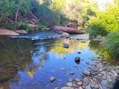 A calm river with rocks and trees reflecting on the water.
