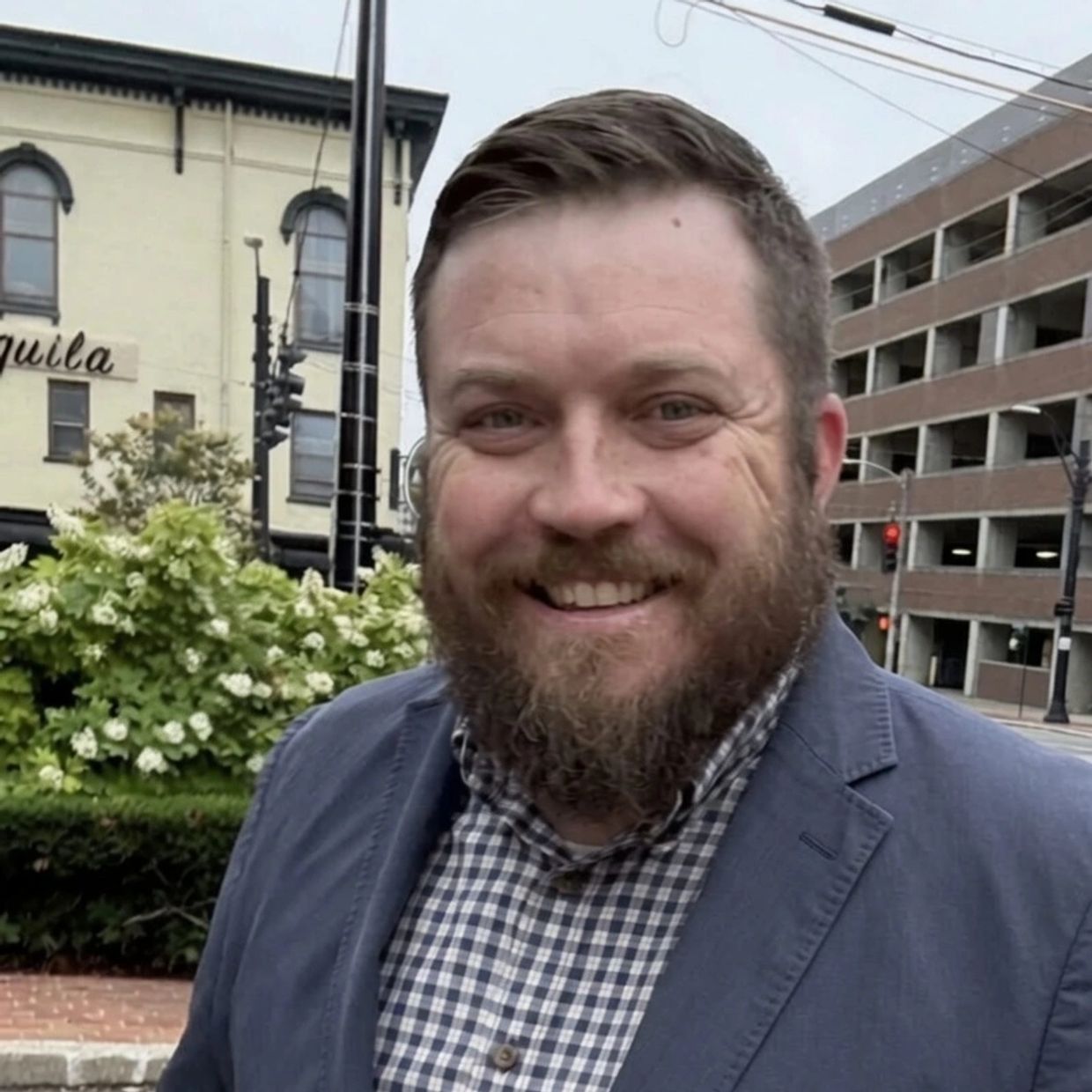 Happy man with beard in blue blazer outdoors.