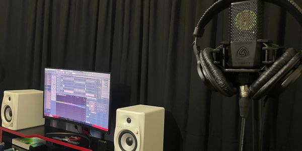 Music production setup with speakers, monitor, and microphone.