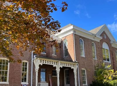 Historic brick building under a bright blue sky with autumn foliage.