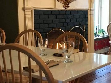 Table set for two near a cozy fireplace in a quaint dining room.
