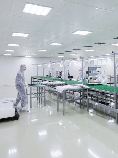 Workers in protective suits operate on a cleanroom production line.