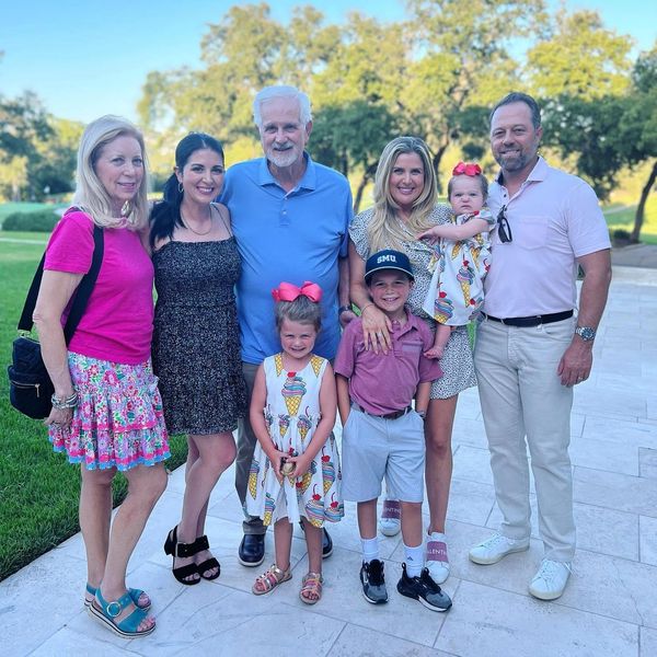 A happy family posing outdoors on a sunny day with smiles and colorful outfits.