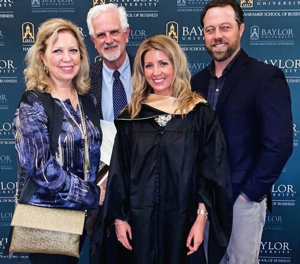 A graduate in cap and gown with three family members at Baylor University.