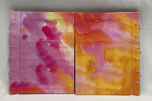 An outside shot of a closed book, which has two sides and is covered in pink and orange.