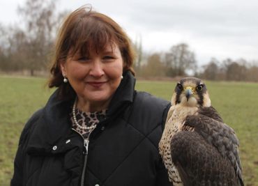 Woman outdoors holding a falcon on her arm.