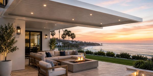 Modern outdoor patio with fire pit overlooking ocean at sunset.