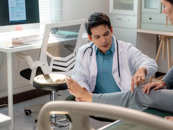 Doctor examining patient's knee in a medical office.