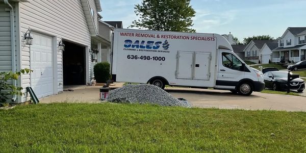 A water removal and restoration truck parked outside a suburban home.