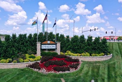 The sign to welcome people to O'Fallon, Missouri on a grassy hill with trees in the background
