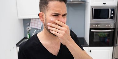 Man covering mouth, feeling nauseous in kitchen.