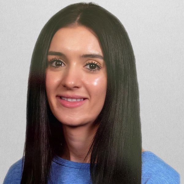 Portrait of a smiling woman with long dark hair and a blue top.