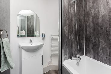Master bedroom's ensuite, with tub, shower, heated towel rail, and vanity unit.