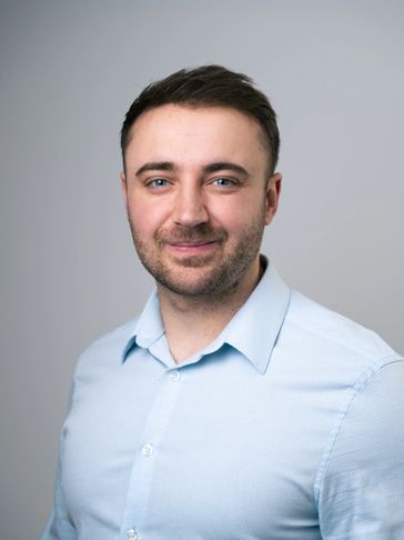 Smiling young man in light blue shirt.