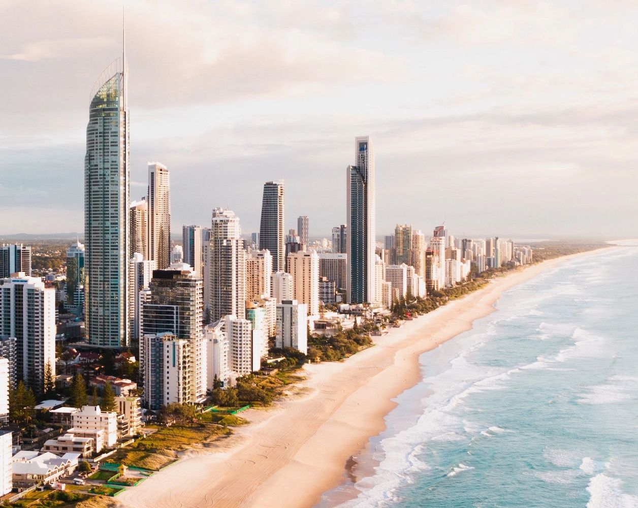 City skyline with tall buildings along a sandy beach and ocean.