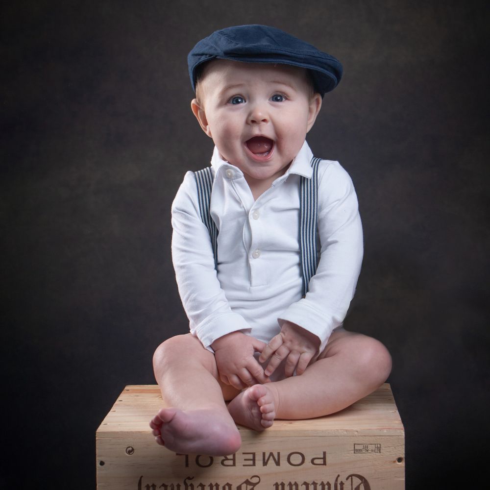 Smiling baby sitting on a wooden box.