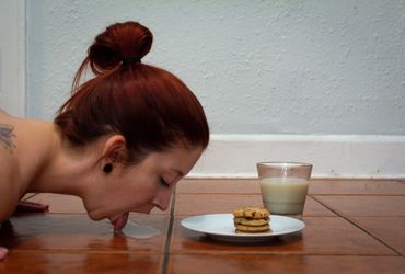 nude woman licking milk and cookies off of the floor 