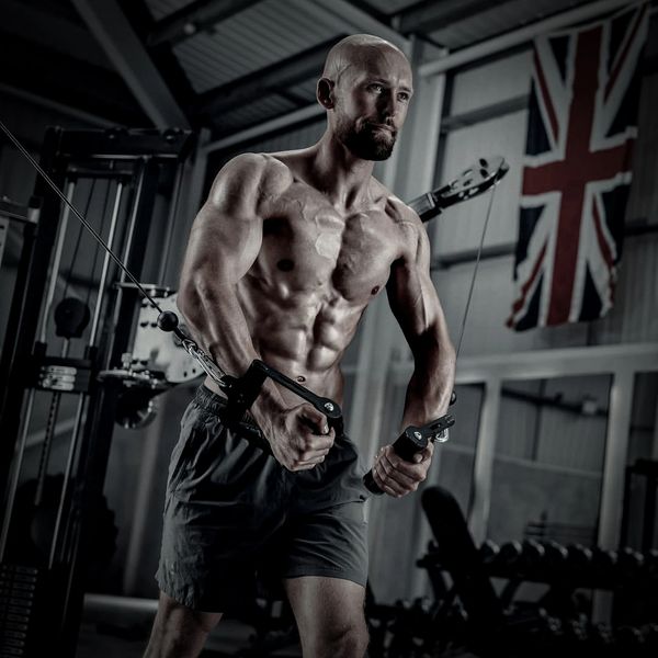 Muscular man performing cable chest fly exercise in gym.