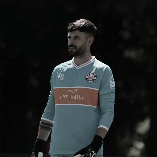 Goalkeeper in teal jersey focused on the game.