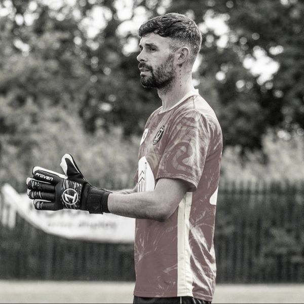 Goalkeeper in action wearing gloves and a sports jersey.