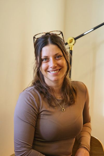 Smiling woman with glasses on her head sitting indoors.