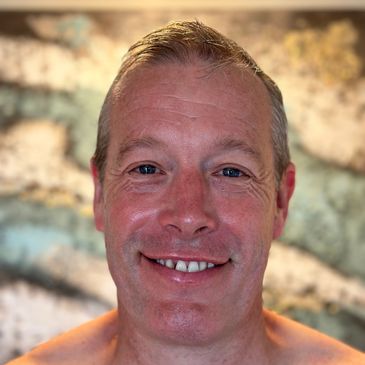 Smiling man with short hair and blue eyes in a close-up portrait.