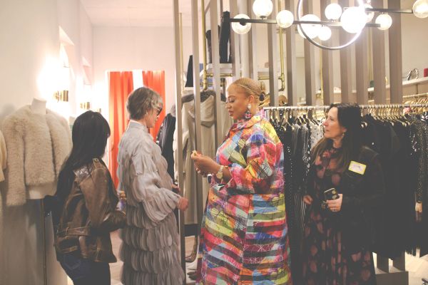 Four women shopping and discussing clothes in a boutique.