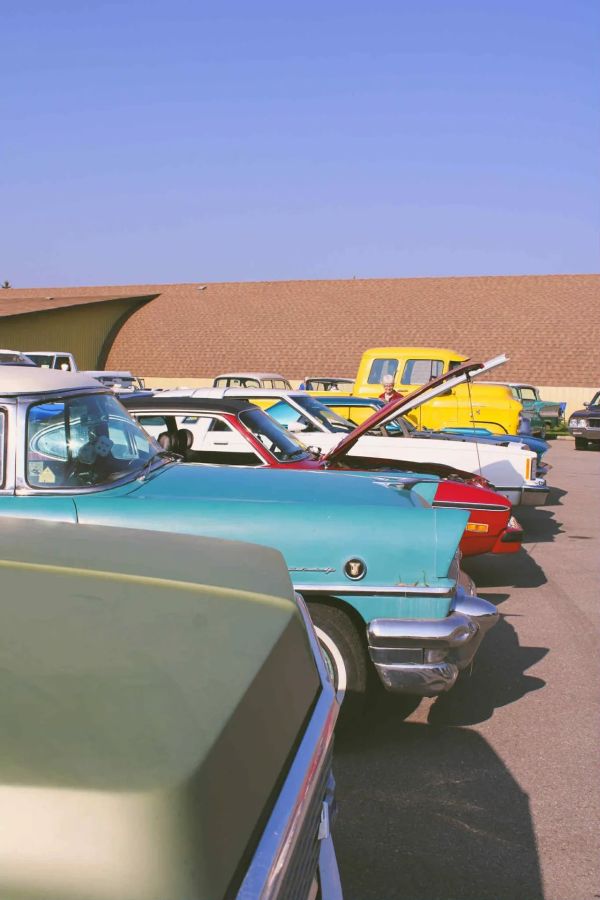 A lineup of vintage cars parked under a clear blue sky.