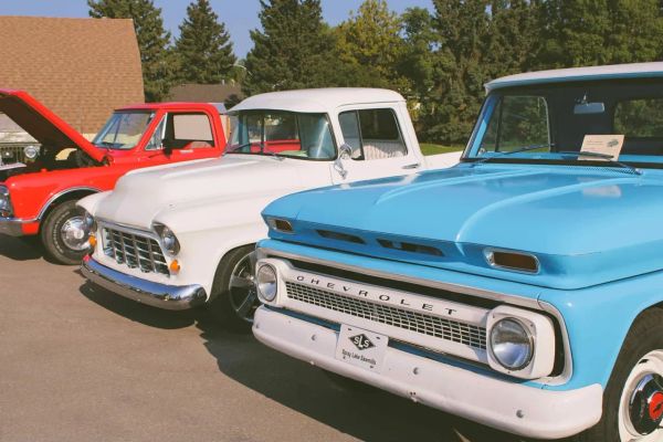 Three vintage Chevrolet pickup trucks parked outdoors in bright sunlight.