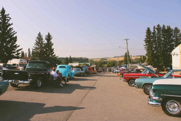Classic cars lined up on both sides of a street at a sunny car show.
