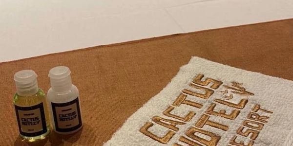 Two small bottles and a towel with 'Cactus Hotel &amp; Resort' embroidery.