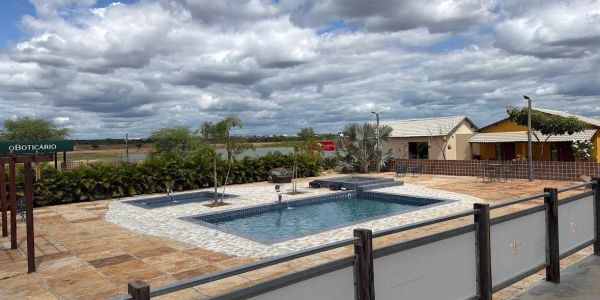 Outdoor swimming pool with cloudy sky and countryside backdrop.