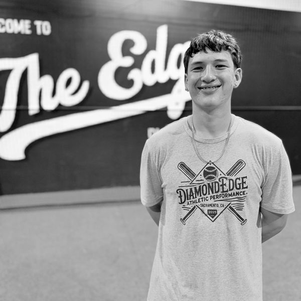 Young man smiling in front of a sports-themed wall.