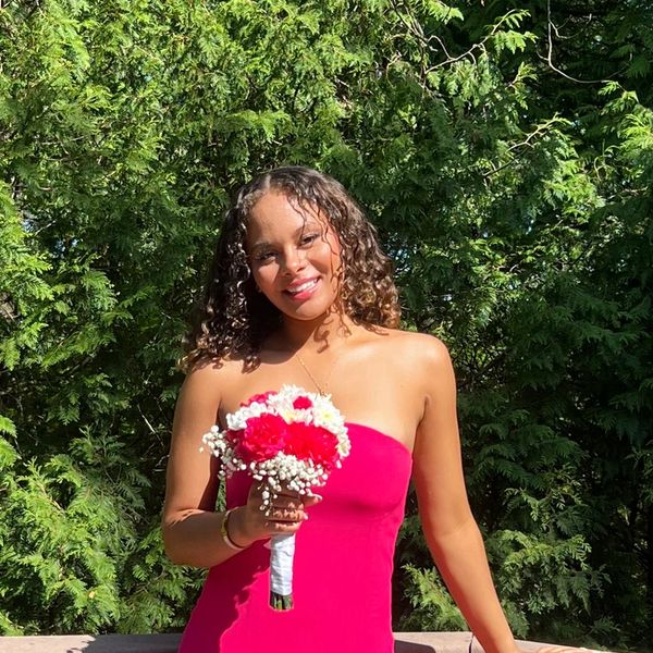 Woman in pink dress holding flowers outdoors.