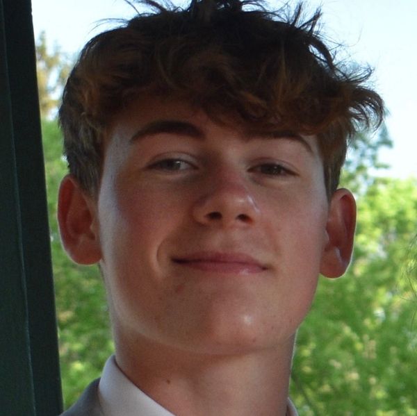 Close-up of a young man with curly hair smiling.