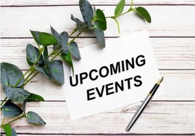 A note with 'Upcoming Events' and a pen on a wooden table with green leaves.