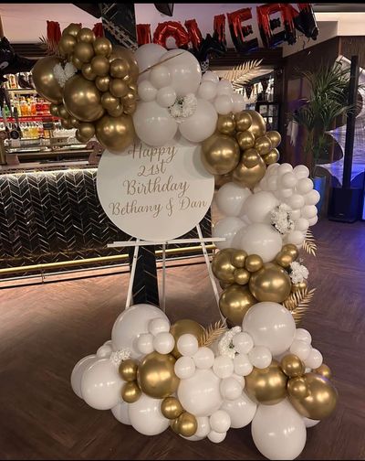 Elegant gold and white balloon arrangement for a 21st birthday celebration.