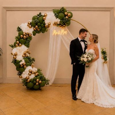 Bride and groom standing beside a decorative balloon arch at their wedding.