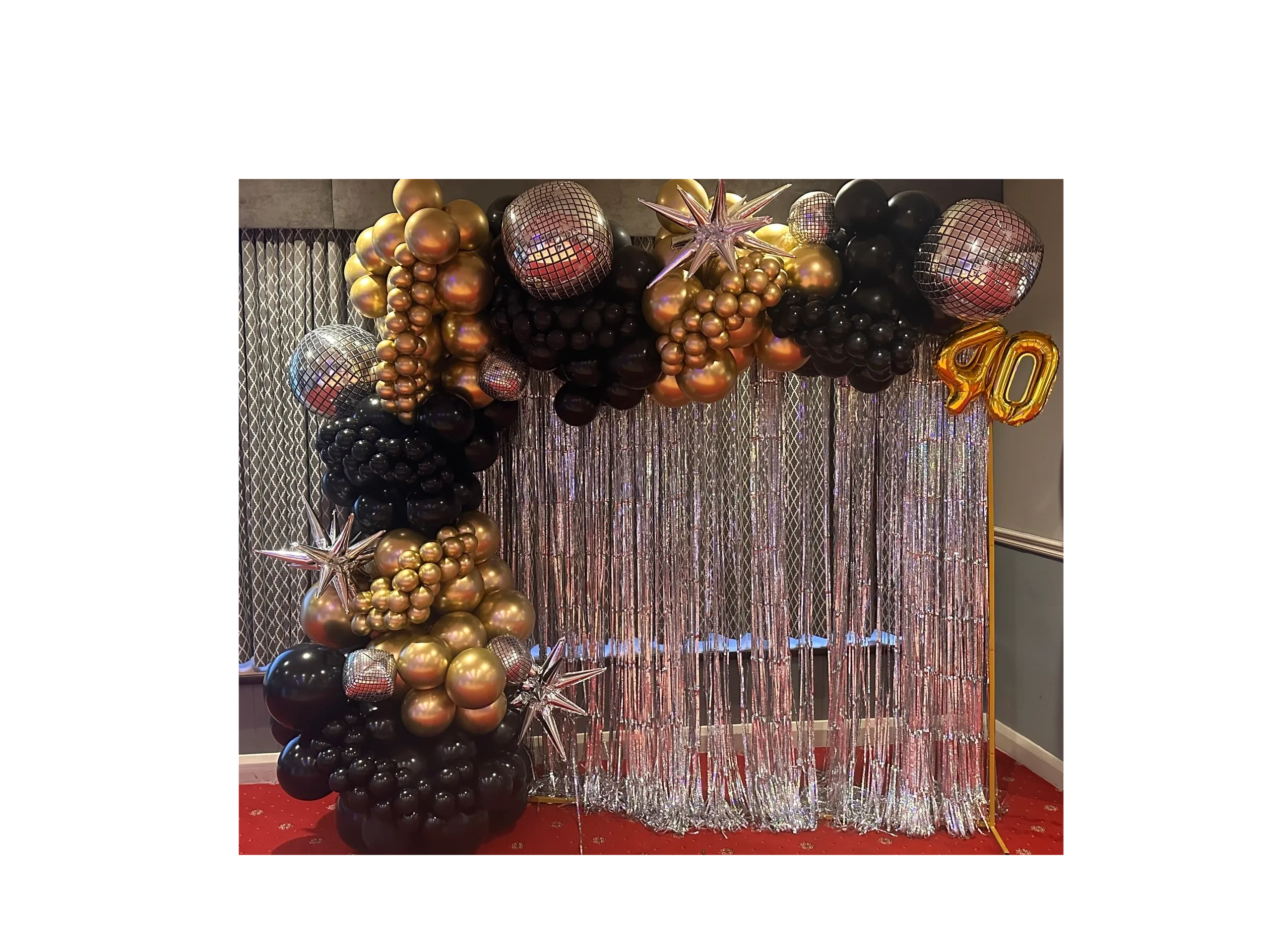Elegant black and gold balloon arch with silver fringe curtain for a 40th birthday celebration.
