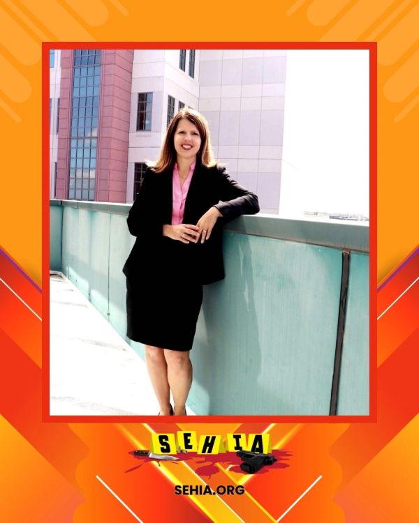 Professional woman in a black suit standing outdoors by a railing.