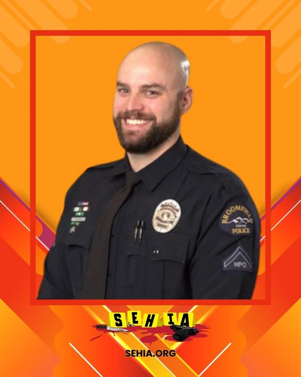 Smiling police officer in Broomfield uniform against an orange background.